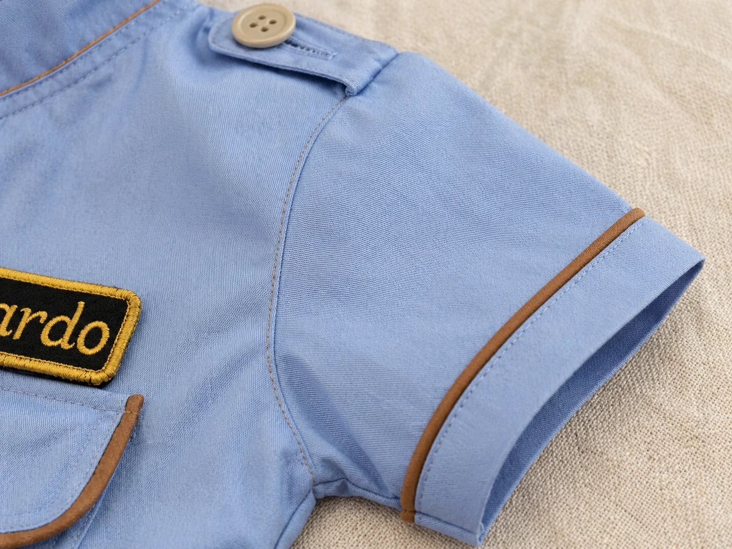 Macro da manga curta com vivo cobre na barra + ombro com lapela e botão · azul claro tricoline · acabamento alfaiataria Costuragi